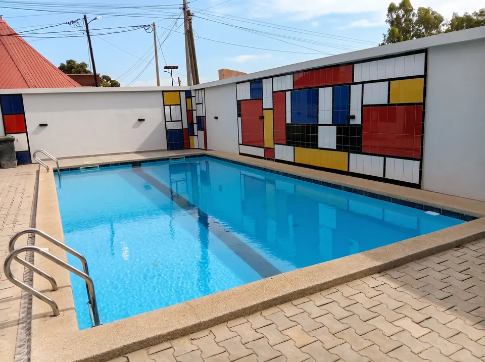 La piscine et le mur de carreaux colorés aux lignes noires, sous un ciel bleu